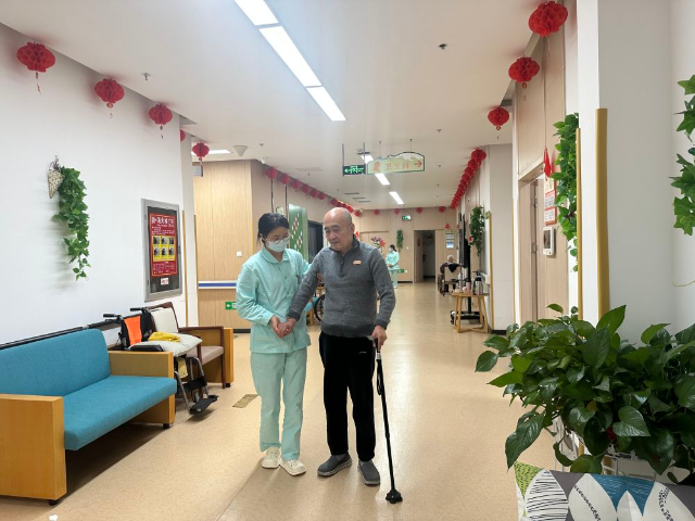 1715569007758405.jpg 護(hù)理員喬瑞霞正在輔助入住中心的全托老人行走.jpg